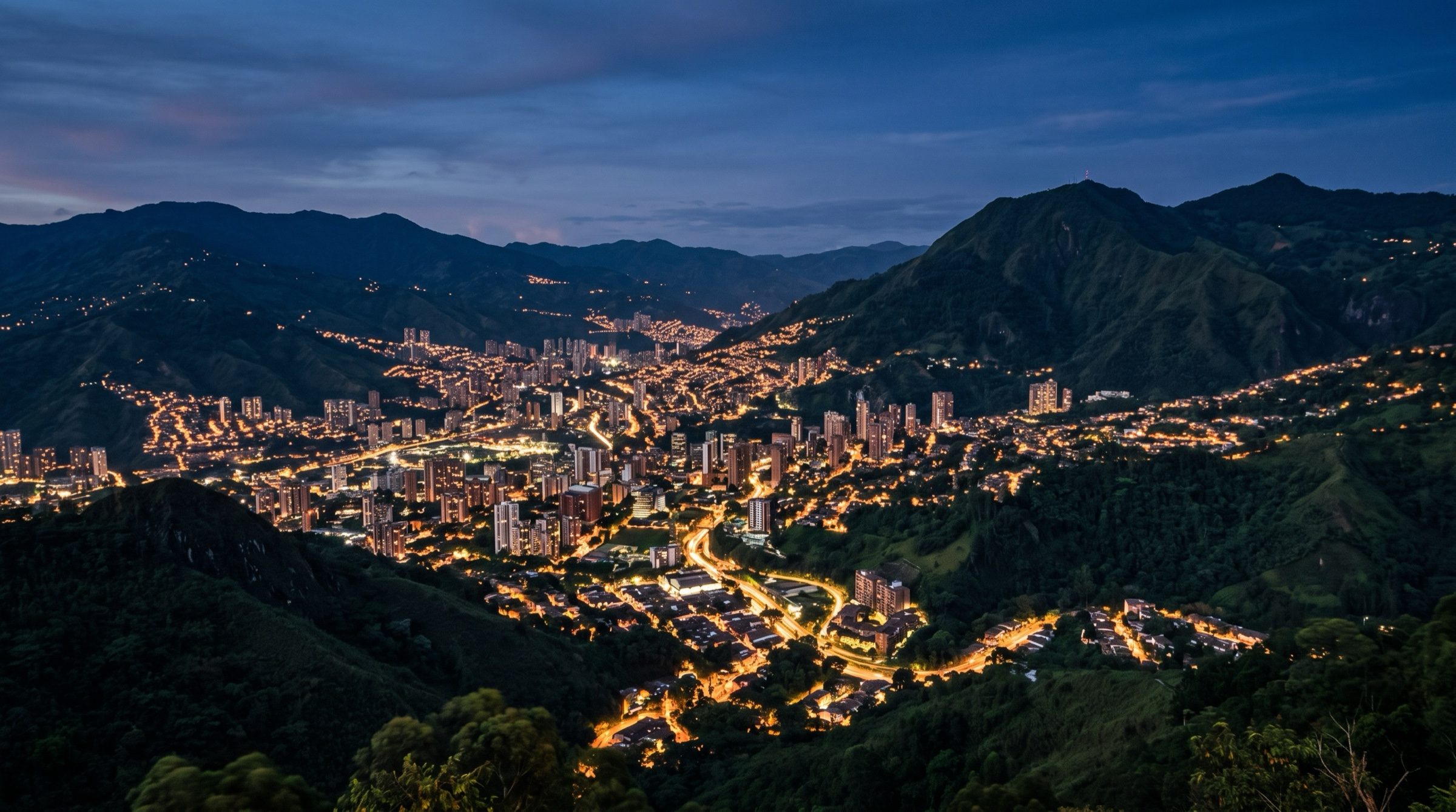 Medellin valley city lights at dusk surrounded by green mountains