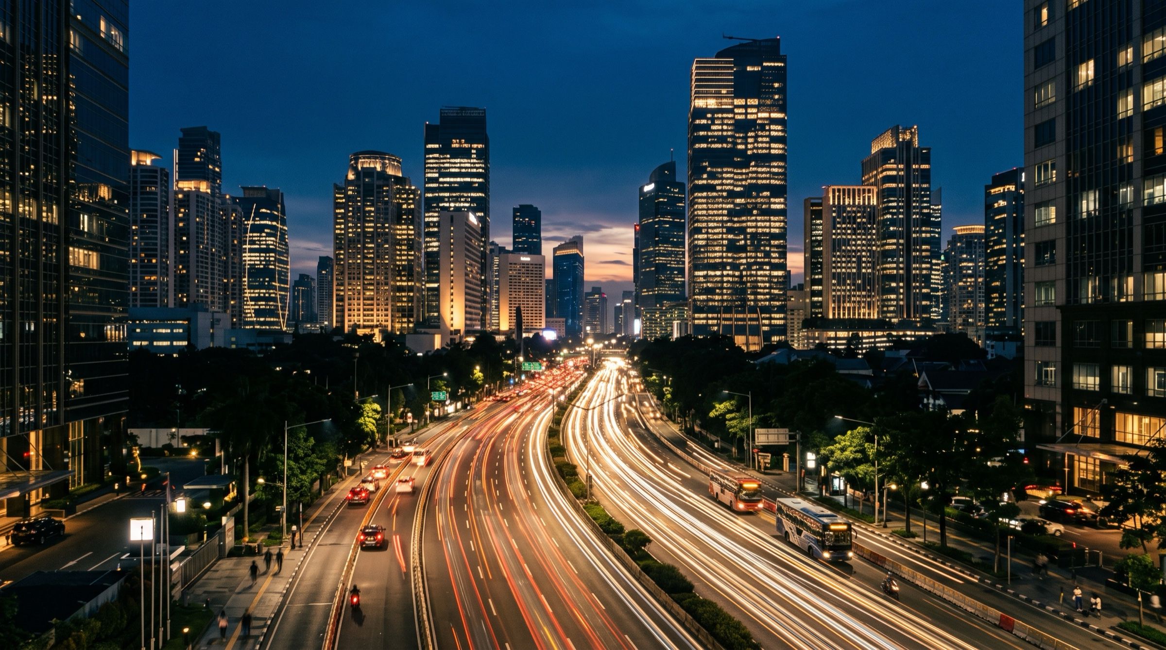 Jakarta skyline at dusk with traffic light trails along a wide boulevard