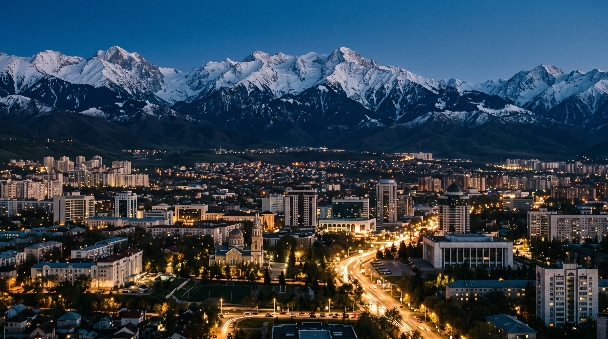 Almaty city at dusk with the snow-capped Tian Shan mountains behind