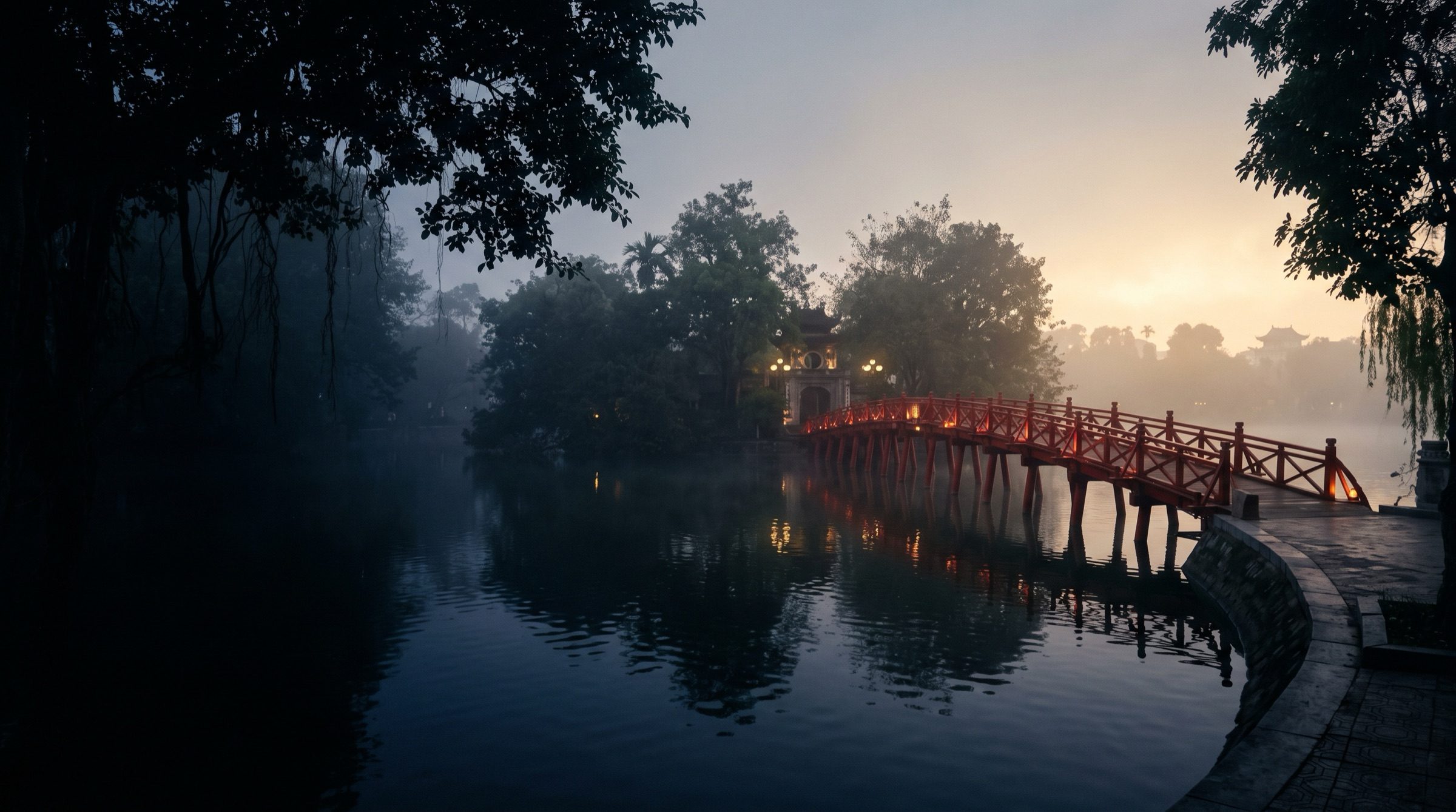 Hoan Kiem Lake in Hanoi at dawn with mist and a red wooden bridge