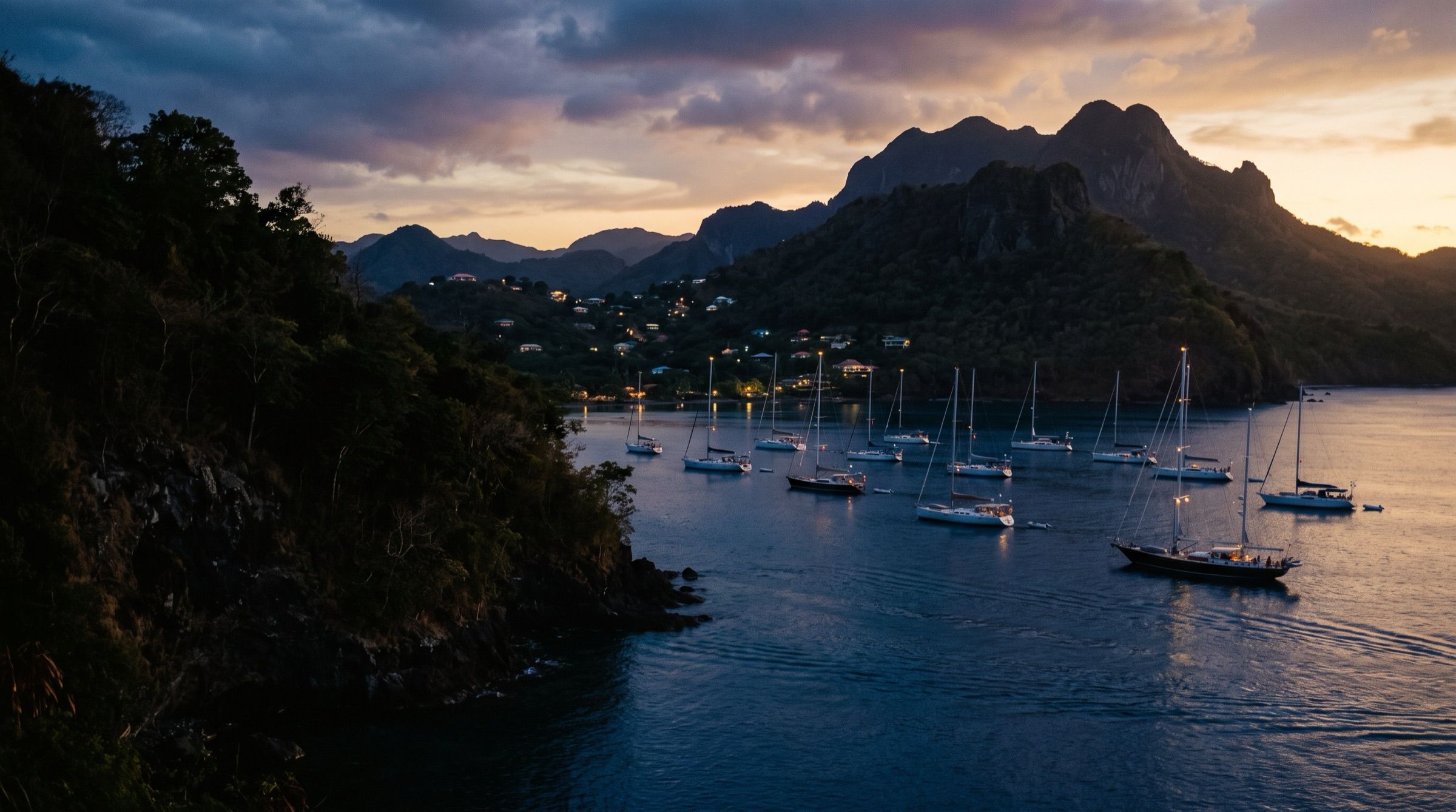 A quiet Caribbean bay at dusk with sailing yachts at anchor and volcanic hills, deep blue water