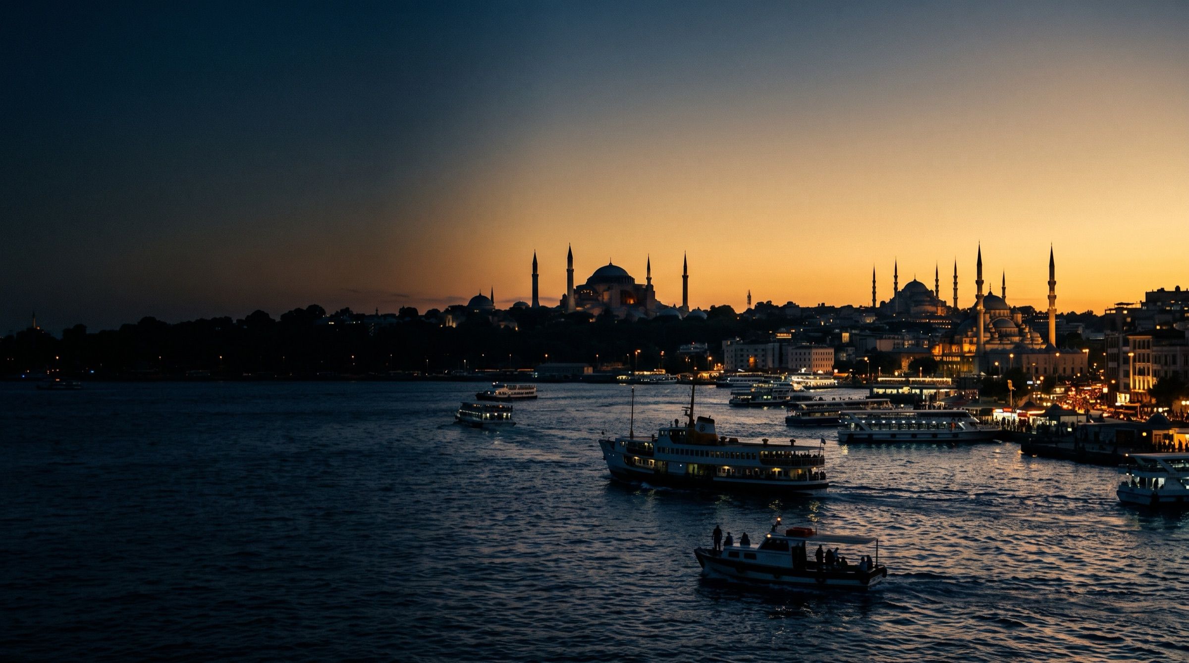 The Bosphorus in Istanbul at sunset with mosque domes and minaret silhouettes, ferries on the water