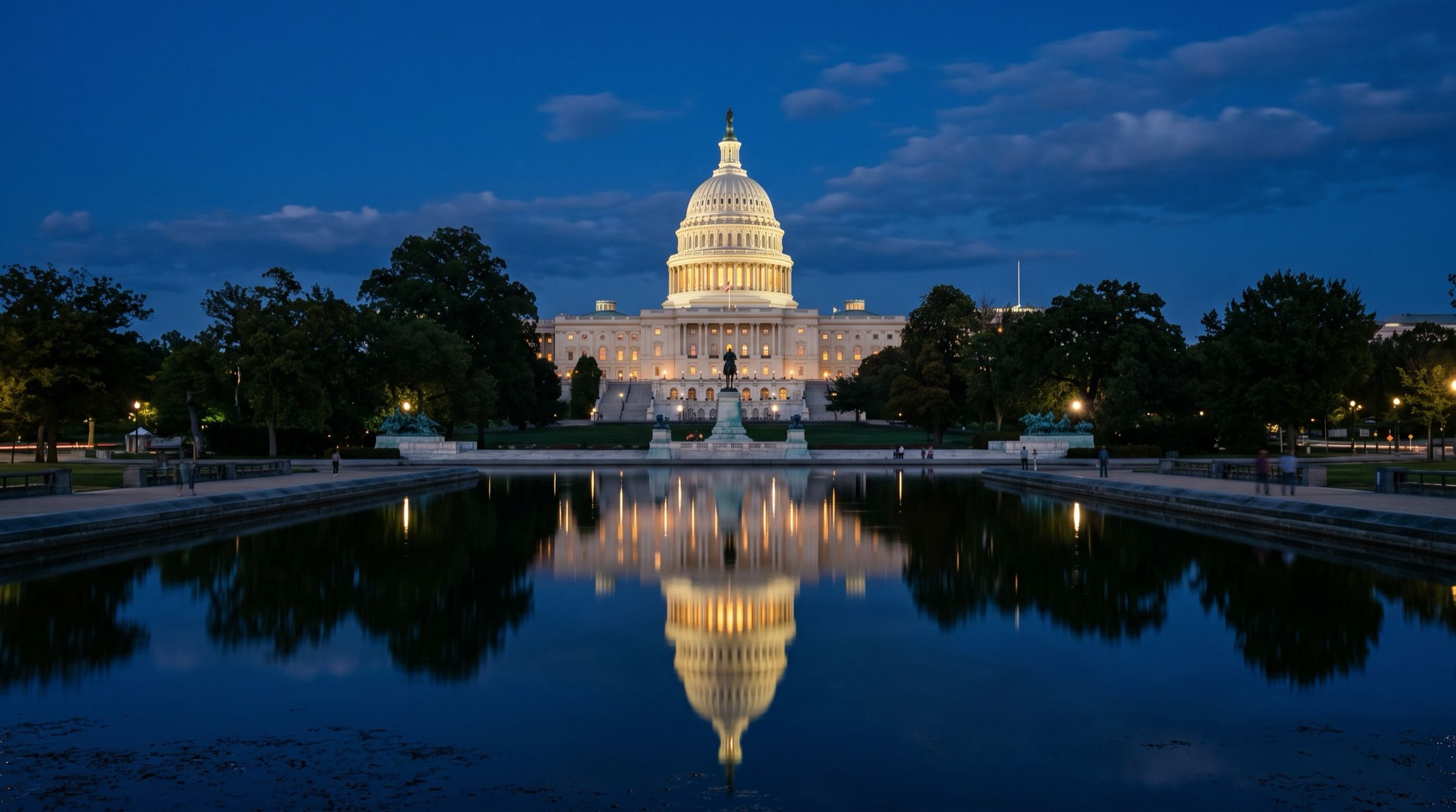 The United States Capitol dome at blue hour seen across a reflecting pool, warm lights on the facade