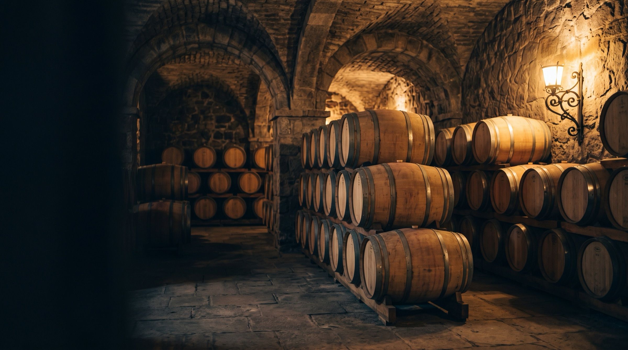Oak barrels in a stone wine cellar in Mendoza, warm lamp light, vaulted ceiling